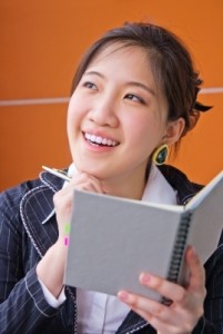 A woman with pen and blank book thinking about what kind of non-fiction book to write.