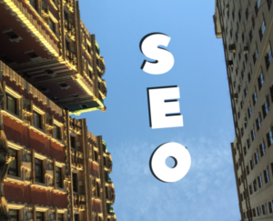 SEO search engin optimization written as clouds in a sky between two tall buildings as viewed from the ground.